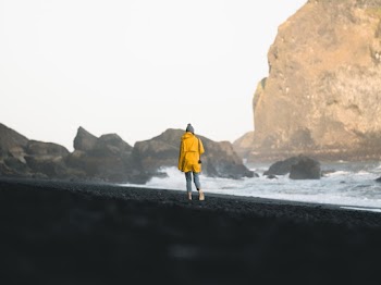 Woman in Yellow Jacket Walking Along Shore