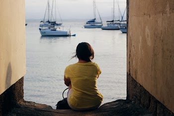 Woman in Yellow Shirt Sitting Near Body of Water