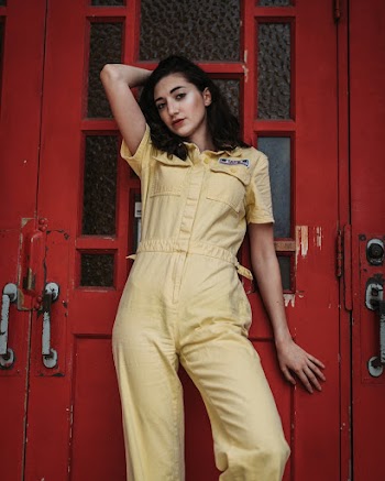 Woman in Yellow Suit Leaning on Red Painted Door