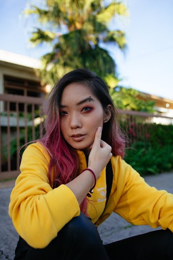 Woman in Yellow Sweater and Black Pants Sitting in Sidewalk