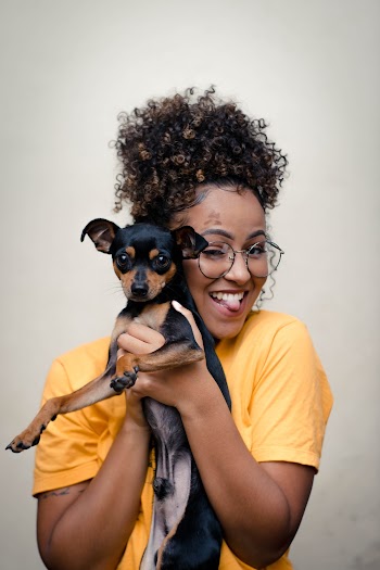 Woman in Yellow Top Carrying Short-coated Black and Brown Dog