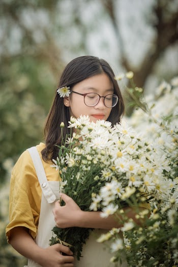 Woman in Yellow Top Holding White Daisy Flowers