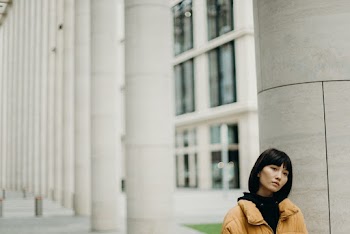 Woman in Yellow Top Standing Beside White Column