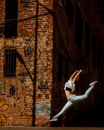 Woman Jumping Near Brick Building