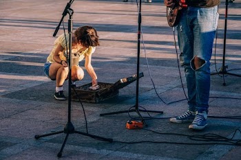 woman kneeling in front of person holding guitar