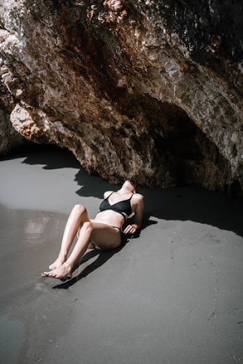 Woman Laying On Sand Near Rock Formation
