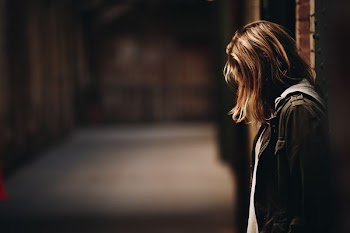 woman leaning against wall facing down
