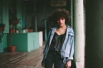 woman leaning against white pillar
