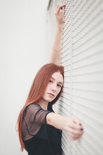 Woman Leaning Against White Wall