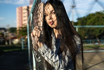Woman leaning forward on a chain-link fence