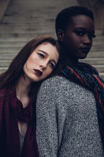 woman leaning her head to another woman during daytime