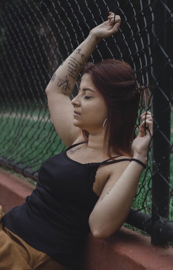Woman Leaning On Black Cyclone Fence