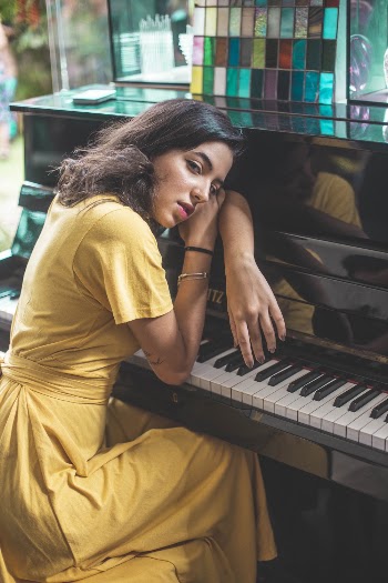 Woman Leaning on Black Piano Posing