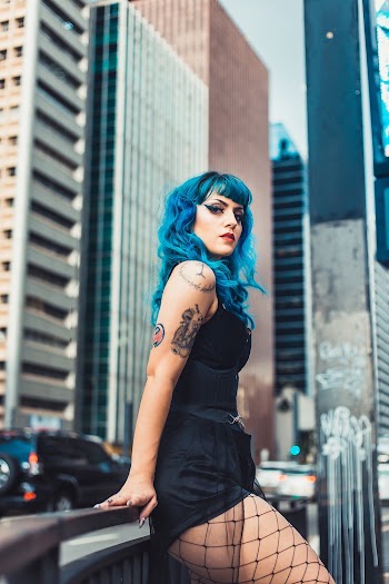 Woman Leaning on Black Railing Near Buildings