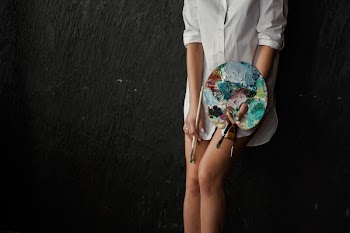 Woman Leaning on Black Surface Holding Paint Tray and Brushes