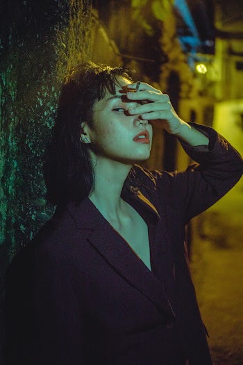 Woman Leaning on Black Wall Outdoors