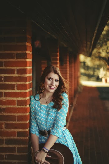 Woman Leaning on Brick Wall While Holding Cowboy Hat