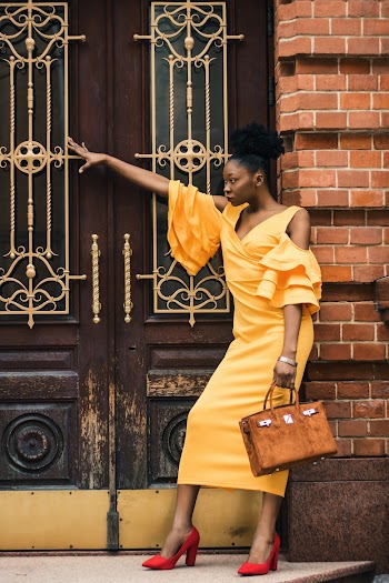 Woman Leaning on Brick Wall While Holding Handbag
