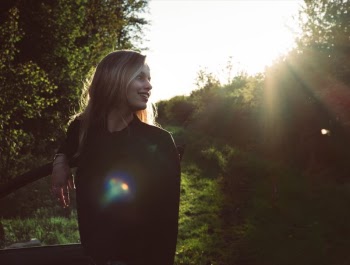 Woman Leaning on Car Door Under Sunny Sky