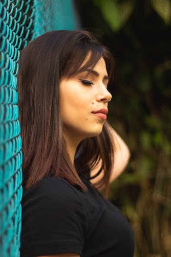 Woman Leaning On Chain Link Fence