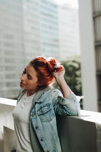 Woman Leaning on Concrete Panel Touching Her Hair