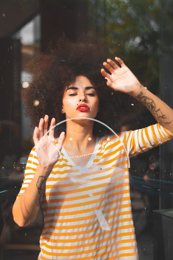 Woman Leaning on Glass Wall Wearing Orange-and-white Striped Crew-neck T-shirt
