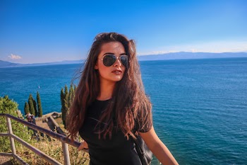 Woman Leaning on Gray Metal Rail Near Ocean