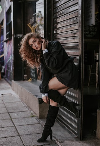 Woman Leaning On Shutter Door On Sidewalk