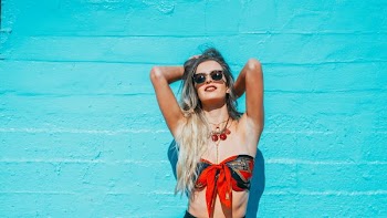 woman leaning on teal wall while facing up