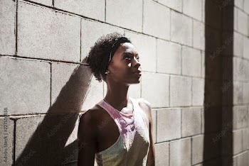 Woman leaning on wall during sunny day