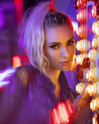 Woman Leaning on Wall Filled With Lights