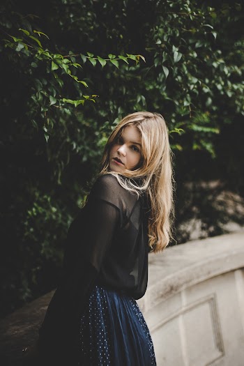 Woman Leaning on Wall Near Green Leafed Tree