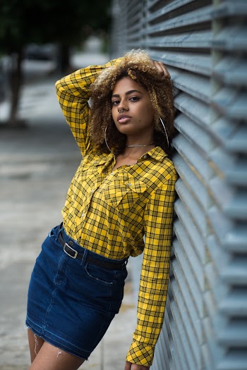 Woman Leaning On Wall Wearing Dress Shirt And Denim Skirt