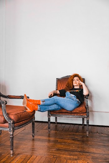 Woman Leaning on Wooden Armchair With Both Legs Resting on Another Chair