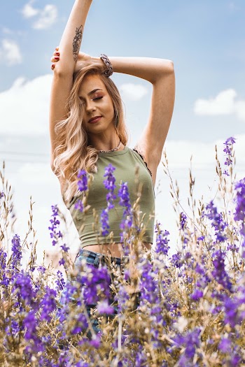 Woman Lifting Hands While Facing Purple Flowers