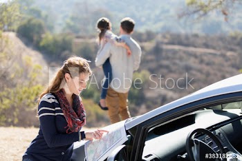 Woman looking at map outside car at sunny roadside