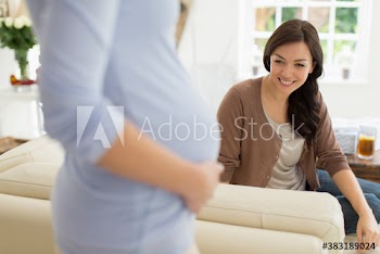 Woman looking at pregnant friend baby bump