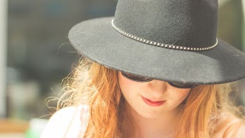woman looking down wearing black bowler hat