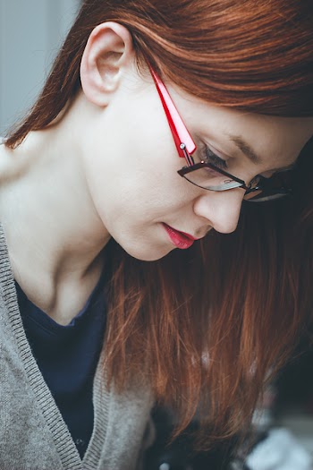 Woman Looking Down Wearing Red Eyeglasses