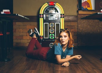 Woman Lying Forward on Parquet Floor in Front of Jukebox