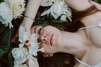 woman lying near white petaled flower