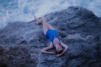 woman lying on boulder neat water