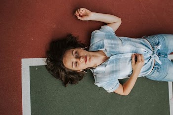 woman lying on floor while closing her eyes