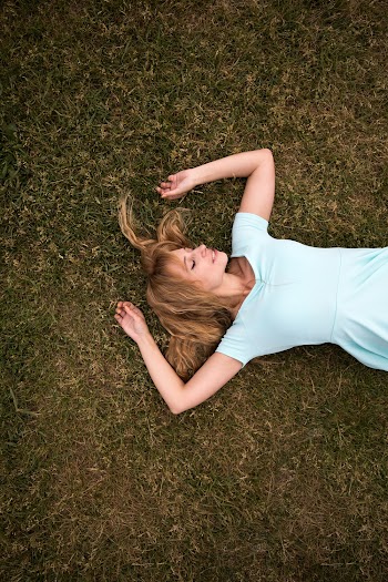 Woman lying on her back on the grass with her eyes closed