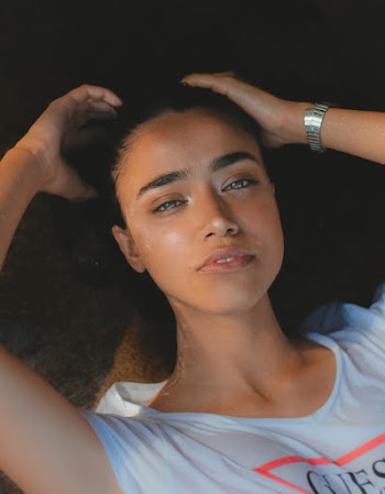 Woman Lying While Wearing White and Red Guess Shirt