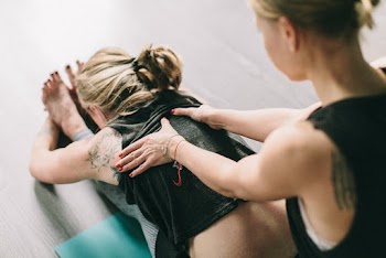 Woman Massaging Back Of Woman Sitting On Floor