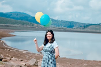 Woman Near Seashore Holding Balloons