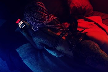 Woman on her back Laying in Bed Holding Phone