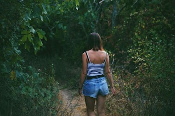 woman on pathway between trees