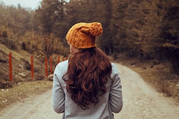 woman on pathway between trees